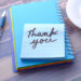 青いボールペンと手帳の上に「Thank you」と書かれたメモ